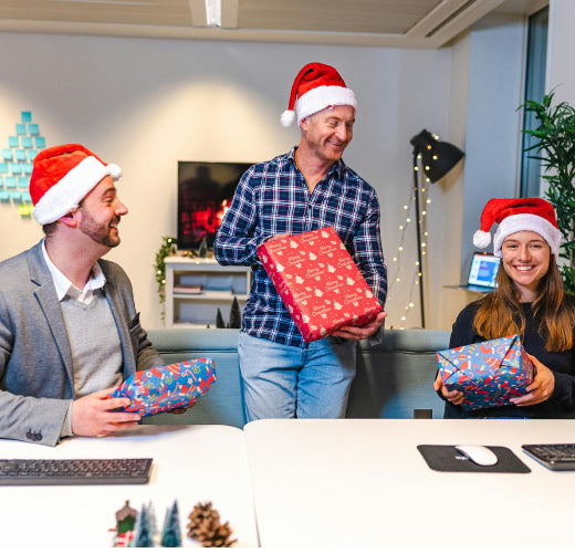 three office workers exchanging christmas gifts