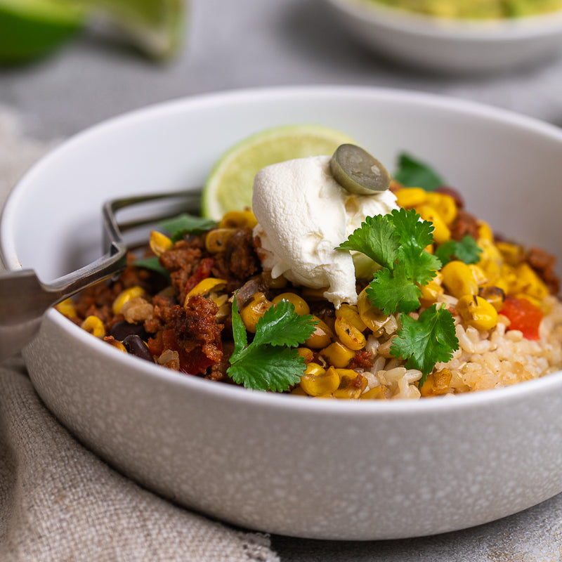  bowl of Mexican-style rice with beans, corn, and sour cream on a textured surface