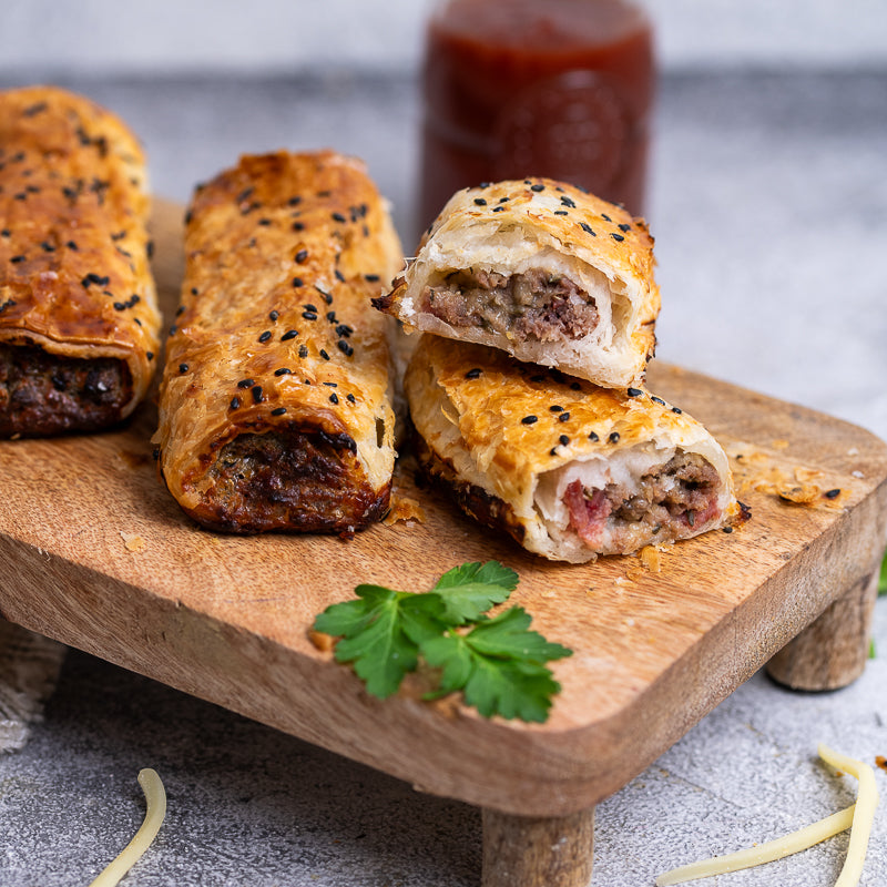 Beef Cheese and Bacon sausage rolls on a wooden board with a blurred background