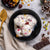 Bowl of sicilian cassata ice cream with fruits and nuts on a textured surface with a gold spoon and chocolate bar.
