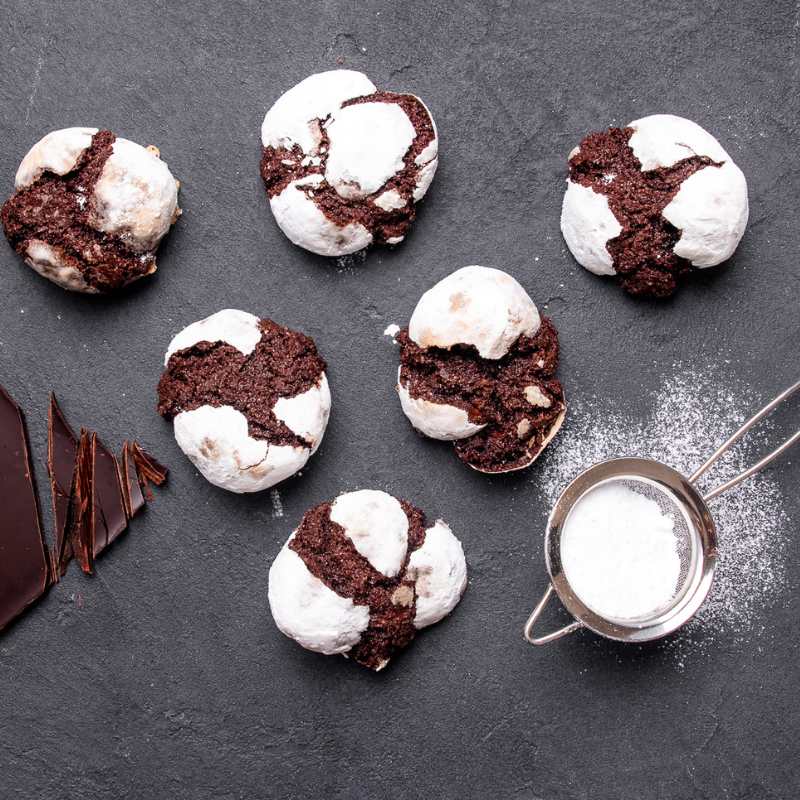 Image of 6 Brownie Bites on a table with chocolate and icing sugar