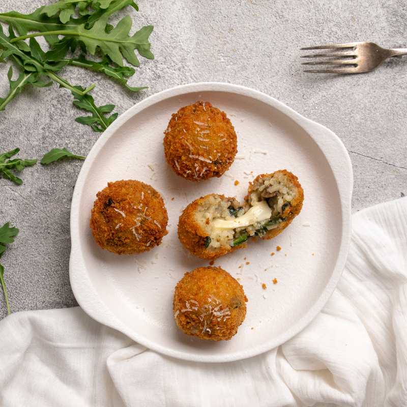 Davide&#39;s Spinach &amp; Mushroom Arancini on a plate with cheese oozing