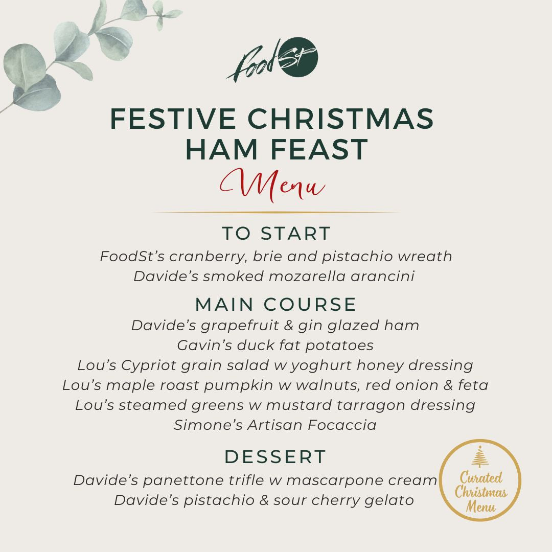 Festive Christmas ham feast with dried oranges and pine cones on a wooden board.