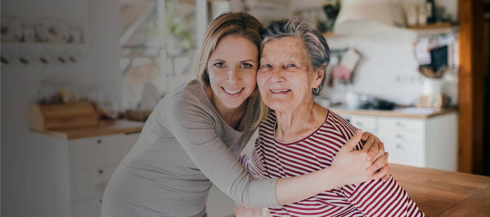 Woman embracing an elderly woman in a home setting