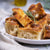 Platter of focaccia bread slices with a small bowl of olive oil and rosemary on a light background