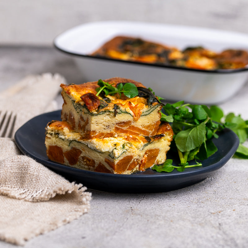 Slice of spinach and cheese quiche on a blue plate with a blurred background