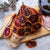 Dried blood oranges on a wooden board with a small bowl of glaze and a citrus reamer.