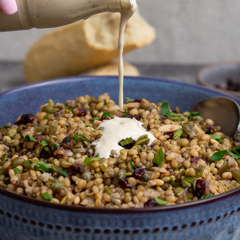 A prepared cypriot grain salad dish served in a bowl, garnished with herbs and accompanied by a side of yogurt dressing and bread.