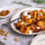 Plate of roasted pumpkin cubes with maple syrup onions and feta cheese on a textured surface.