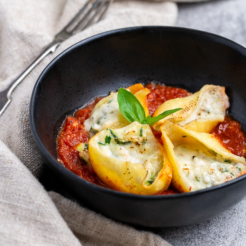 Paolo's Zucchini and Ricotta Pasta Shells in a black bowl, with basil 