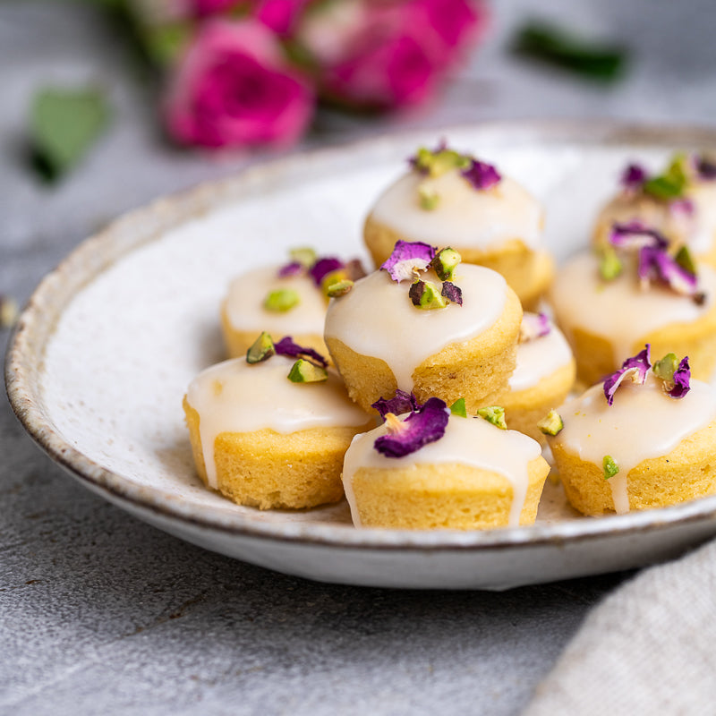Persian Love Cakes with rose petals and icing on a plate with pistachios 