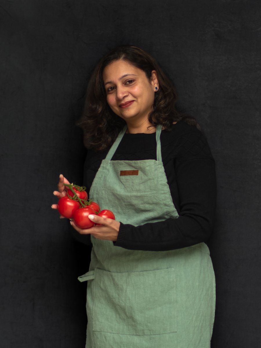 Photo of Manjari in a green apron holding tomatoes