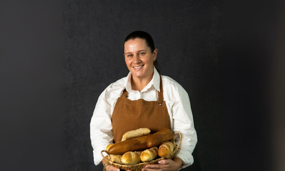 Food St cook Zoie wearing an apron holding a basket of bread against a black background