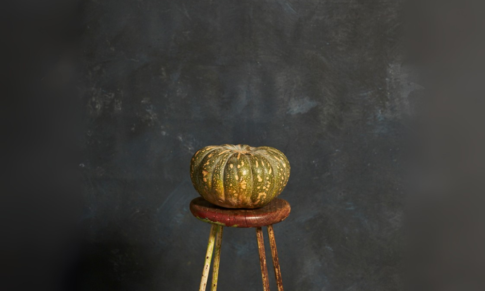 Small pumpkin on a wooden stool against a dark textured background