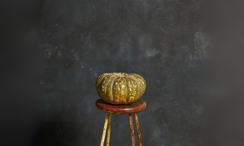 Small pumpkin on a wooden stool against a dark textured background