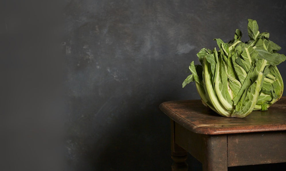 Green leafy vegetable cauliflower on a wooden table with a dark background