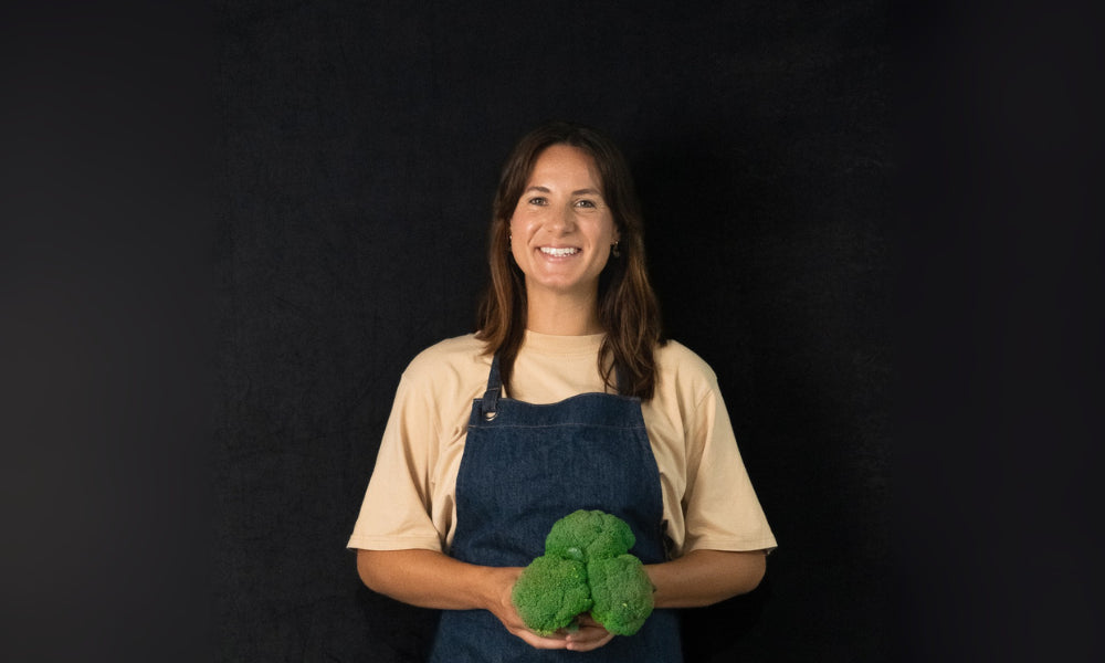 Image of FoodSt cook, Anize holding broccoli against a black background