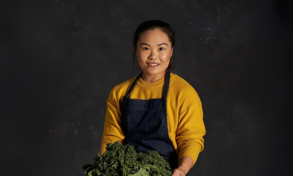 FoodSt cook Cynthia holding kale against a dark background