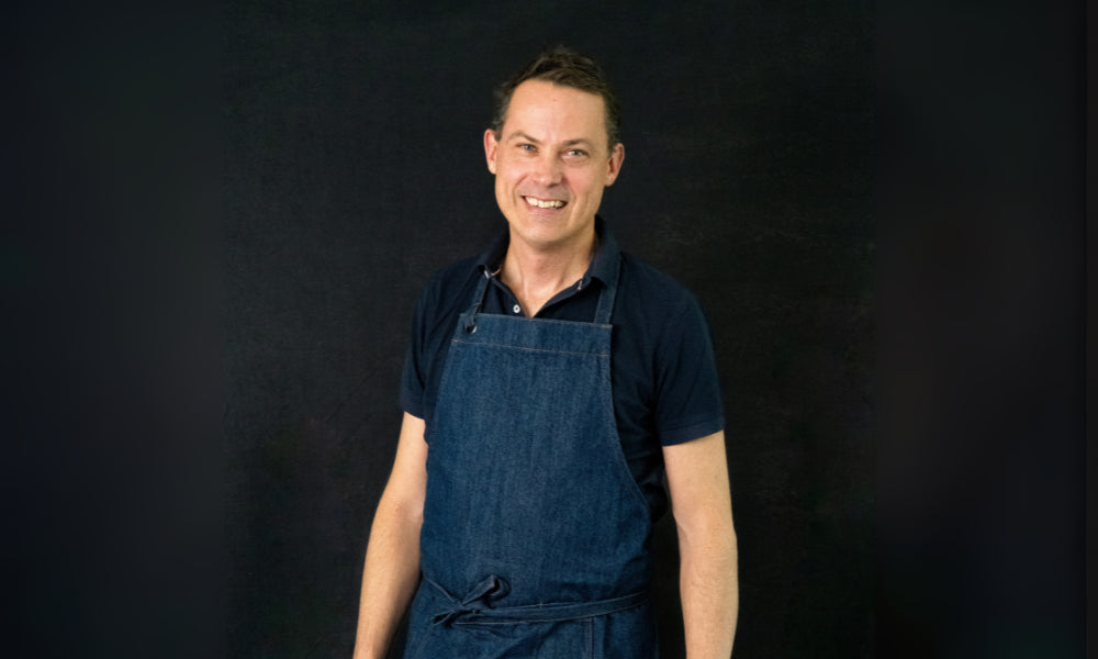 FoodSt cook Gavin wearing a blue apron against a black background