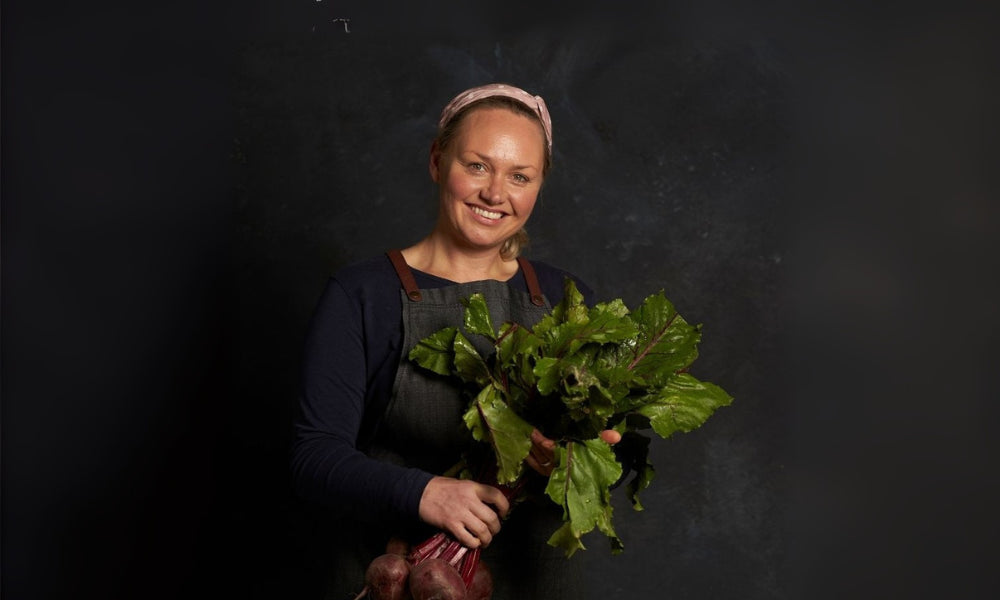FoodSt cook Helen holding a bunch of green leafy vegetables against a dark background