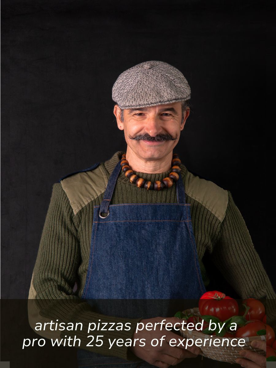 Simone, FoodSt cook wearing a gray flat cap, green knit sweater, and blue denim apron stands against a black background, holding tomatoes. White text at the bottom reads, 'artisan pizzas perfected by a pro with 25 years of experience.