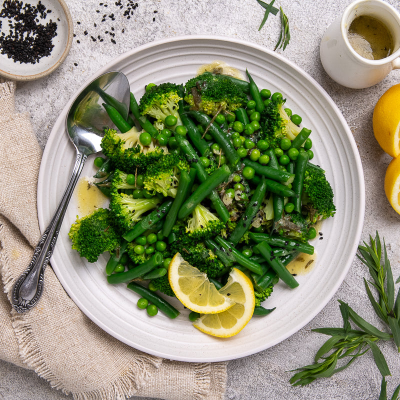 Plate of green vegetables with lemon slices on a light background
