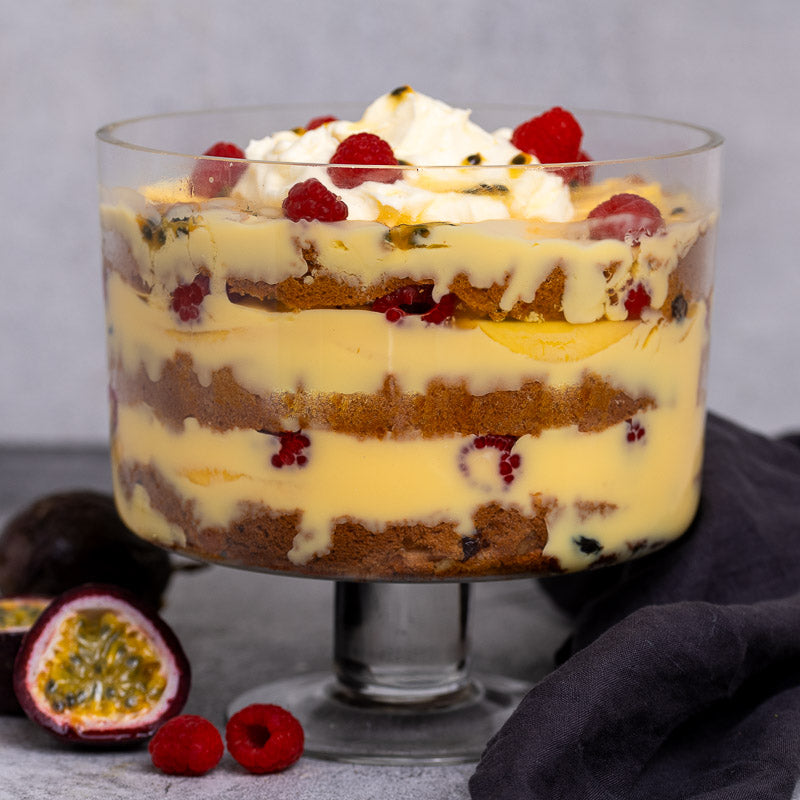Panettone and custard trifle in a trifle glass dish showing layers with raspberries and passionfruit