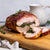 Turkey wrapped in prosciutto Christmas roast with spinach filling on a wooden board, with a blurred background.