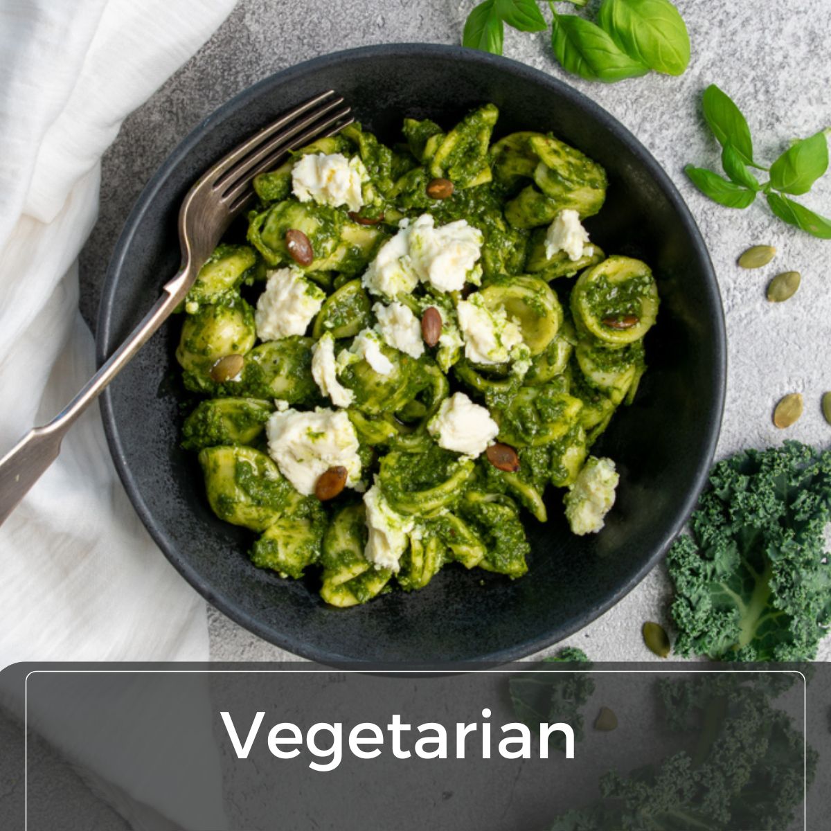 Image of green pesto pasta with feta cheese and pine nuts in a bowl top down image