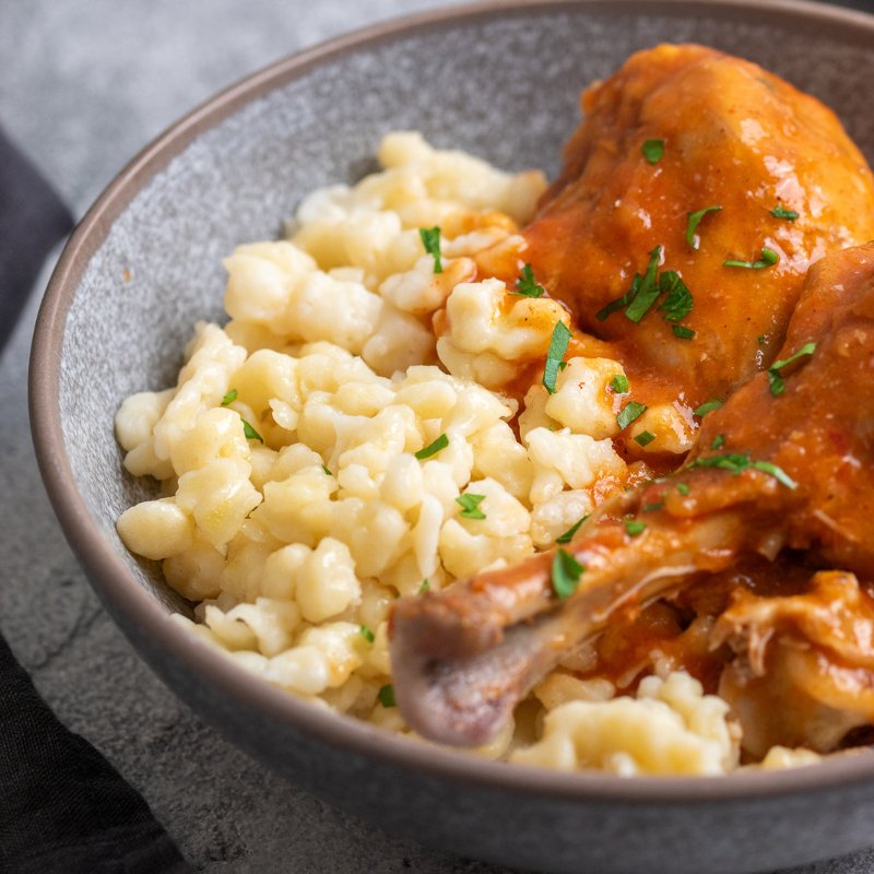 closeup of the Nokedli in a bowl next to the chicken Paprikash