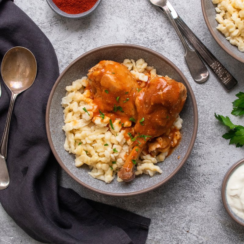 Amalia&#39;s Hungarian Chicken Paprikash with Nokedli in a bowl with spoon and serviette